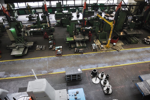 A wide shot of a bustling factory floor where military equipment is being manufactured, highlighting the job creation aspect of defense spending. The scene is filled with activity and machinery.
