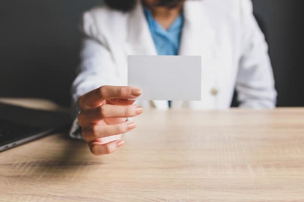A close-up of a hand holding a health insurance card, with a doctor's office visible in the blurred background.