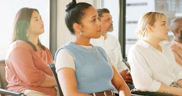 A classroom setting where a diverse group of adults is participating in a job training session. The instructor is demonstrating a practical skill, and the participants are actively engaged and taking notes.