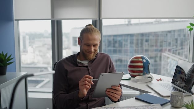 High-angle, medium shot of a smiling employee using an online benefits portal on their tablet. Visual elements include a bright, modern office space in the background.